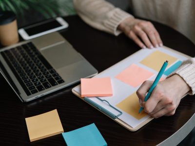 closeup-shot-university-student-hand-holding-pen-writing-information-sticky-note